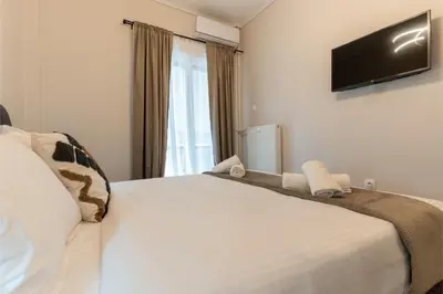 a bedroom with a white bed with a television on the wall at Athenian Secret Key Residence in Athens