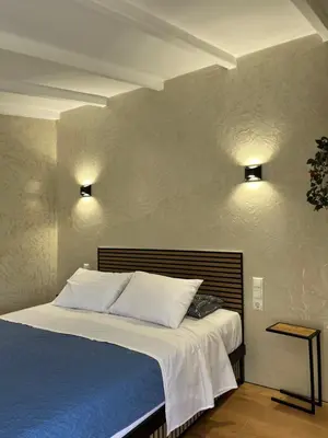 a bed in a bedroom with two lights on the wall at Boutique Eptalofos 2 15min from airport and sea in Kouvarás