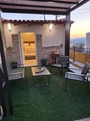 a patio with chairs and tables on the grass at Boutique Eptalofos 2 15min from airport and sea in Kouvarás