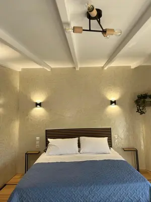 a bedroom with a bed with a blue comforter at Boutique Eptalofos 2 15min from airport and sea in Kouvarás