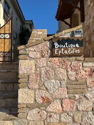 a stone wall with a sign on a building at Boutique Eptalofos 2 15min from airport and sea in Kouvarás