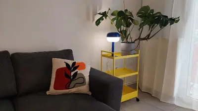 a living room with a couch and a plant and a lamp at Kypseli is a Mood in Athens