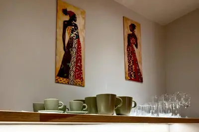a shelf with cups and paintings on the wall at African Adventure Apartment in Piraeus