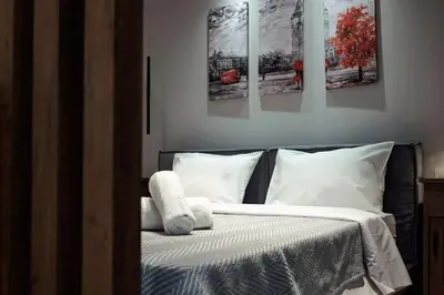 a bedroom with a bed with three paintings on the wall at Big London Apartment in Piraeus in Piraeus