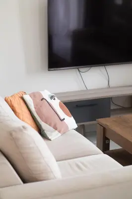 a living room with a white couch and a flat screen tv at Airport city center 4 in Spáta