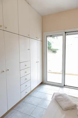a bedroom with white cabinets and a large window at Airport city center 4 in Spáta