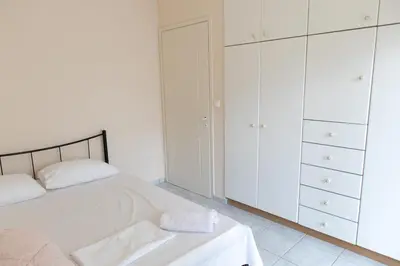 a white bedroom with a bed and white cabinets at Airport city center 4 in Spáta
