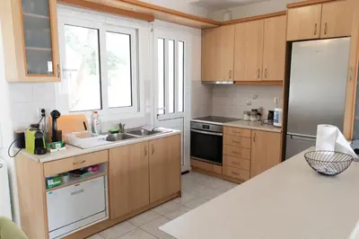 a kitchen with wooden cabinets and a stainless steel refrigerator at Airport city center 4 in Spáta