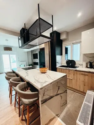 a kitchen with a marble counter top and chairs at Sunlit luxurious flat at pagrati! in Athens