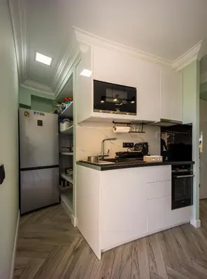 a kitchen with white cabinets and a refrigerator at MORE Apartments in Áyios Yeóryios