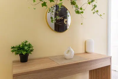 a mirror on a wall above a table with a vase at The Psyri Collection in Athens