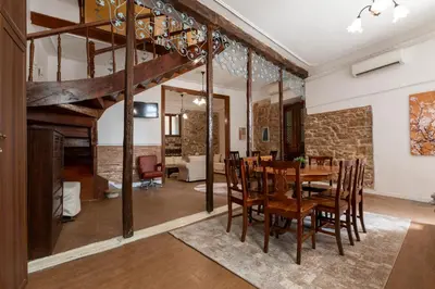 a dining room and living room with a wooden table and chairs at The Psyri Collection in Athens