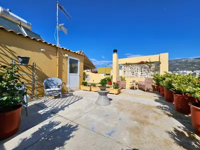 a patio of a house with a chair and plants at Roof Garden Loft in Athens