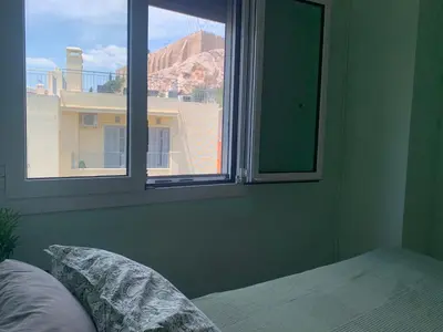 a bedroom with a window with a view of a building at Cosy Plaka flat with view of Acropolis Parthenon in Athens