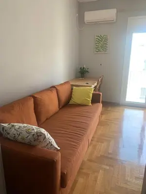 a living room with a brown couch and wooden floors at Cosy Plaka flat with view of Acropolis Parthenon in Athens
