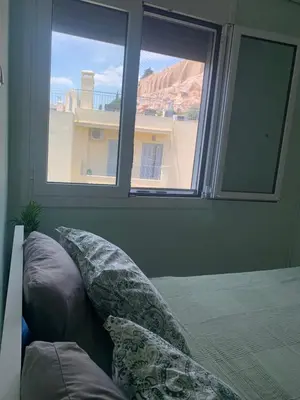 a bedroom with two windows and a bed with pillows at Cosy Plaka flat with view of Acropolis Parthenon in Athens