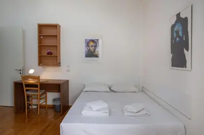 a white bedroom with a bed and a desk at Comfy Apartment In Exarchia Vibrant Neighborhood in Athens