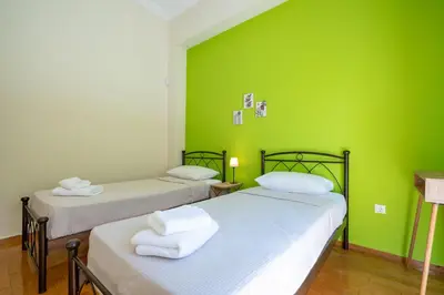two beds in a room with a green wall at Monastiraki Aélia Apartment by ΜΡS in Athens