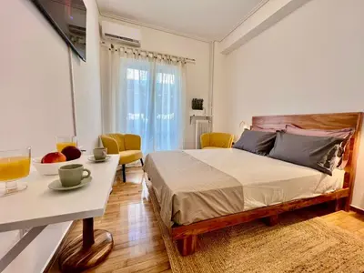 a bedroom with a bed and a table and a room at Bright and stylish Acropolis studio in Athens