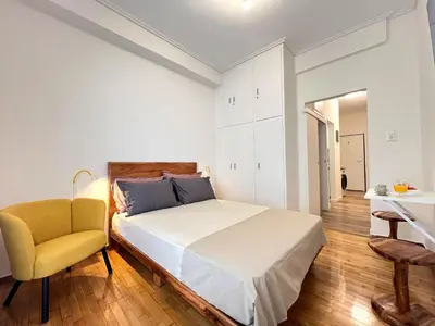 a bedroom with a bed and a yellow chair at Bright and stylish Acropolis studio in Athens