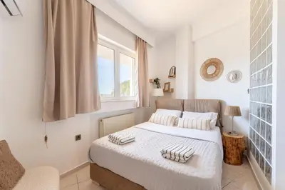 a white bedroom with a bed and a window at Rustic Garden Cabin in Vari