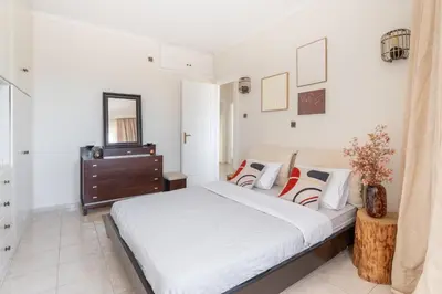 a white bedroom with a bed and a dresser at Rustic Garden Cabin in Vari