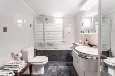 a white bathroom with a toilet and a sink at Rustic Garden Cabin in Vari