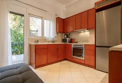 a kitchen with wooden cabinets and a stainless steel refrigerator at Near Metro 3 Bedrooms Fiber 100mbps in Athens