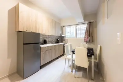 a kitchen with a refrigerator and a table and chairs at Koukaki Comfort - Modern 2BR near Acropolis by ΜΡS in Athens