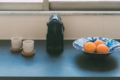 a bowl of oranges on a counter next to two cups at Serenity Penthouse with terrace in Exarcheia in Athens