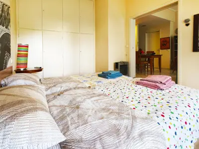 a large bed with colorful sheets and pillows on it at Oulang Easy Stay apartment - Athens Center in Athens
