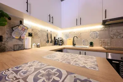 a kitchen with white cabinets and a wooden counter top at Amorgou maisonette in Athens