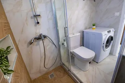 a bathroom with a shower with a toilet and a washing machine at Ariadne - Elegant & Chic House in Egaleo-Athens in Athens