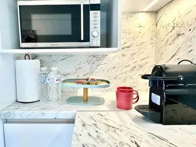 a kitchen counter with a microwave and a table at Urban Calm Glyfada Getaway 2BD in Athens
