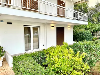 a white house with a balcony and bushes at Urban Calm Glyfada Getaway 2BD in Athens