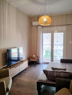 a living room with a flat screen tv and a couch at Dita's Cozy Stay in Athens