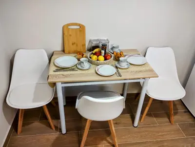 a table with white chairs and a bowl of fruit at Dita's Cozy Stay in Athens