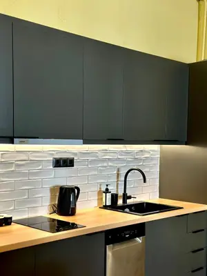 a kitchen with black cabinets and a sink and a counter at Sis Urban,Timeless Elegance in Athens