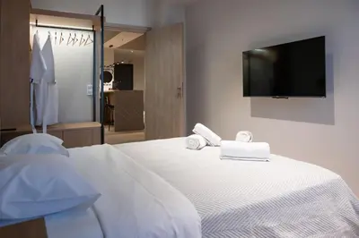 a bedroom with a white bed with towels and a flat screen tv at Never Space Up Apartment in Piraeus