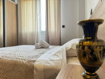 a vase sitting on a table next to a bed at Platon Loft in Athens