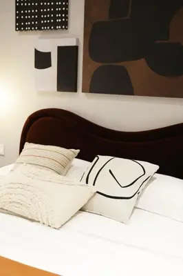a white bed with a black headboard and white pillows at Loft Garden of Port in Piraeus in Piraeus