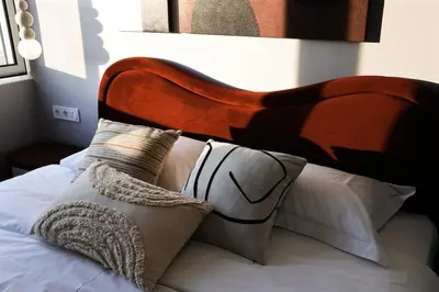 a bed with a wooden headboard and pillows on it at Loft Garden of Port in Piraeus in Piraeus