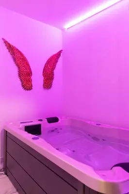 a pink bathroom with a tub with wings on the wall at Apartment with jacuzzi and sauna in Athens