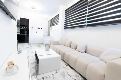a white living room with a white couch and a table at Apartment with jacuzzi and sauna in Athens