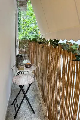a table and two stools in front of a fence at Cozy Apartment in Exarchia, Walk to Athens Museum in Athens