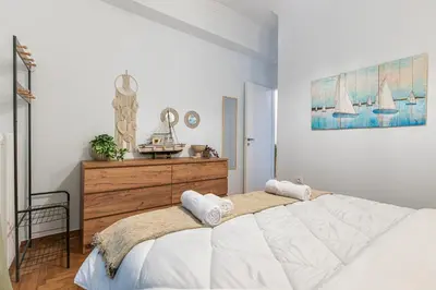 a bedroom with a large white bed and a clock at Cozy Apartment in Exarchia, Walk to Athens Museum in Athens