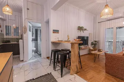 a kitchen and living room with a counter and stools at Cozy Apartment in Exarchia, Walk to Athens Museum in Athens