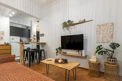 a living room with a flat screen tv and a table at Cozy Apartment in Exarchia, Walk to Athens Museum in Athens