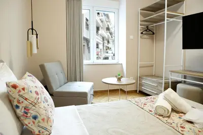 a bedroom with a bed and a chair and a window at Best House Cleo Pasalimani Piraeus in Piraeus