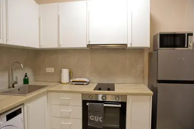 a kitchen with white cabinets and a stove top oven at Best House Electra Pasalimani Piraeus in Piraeus